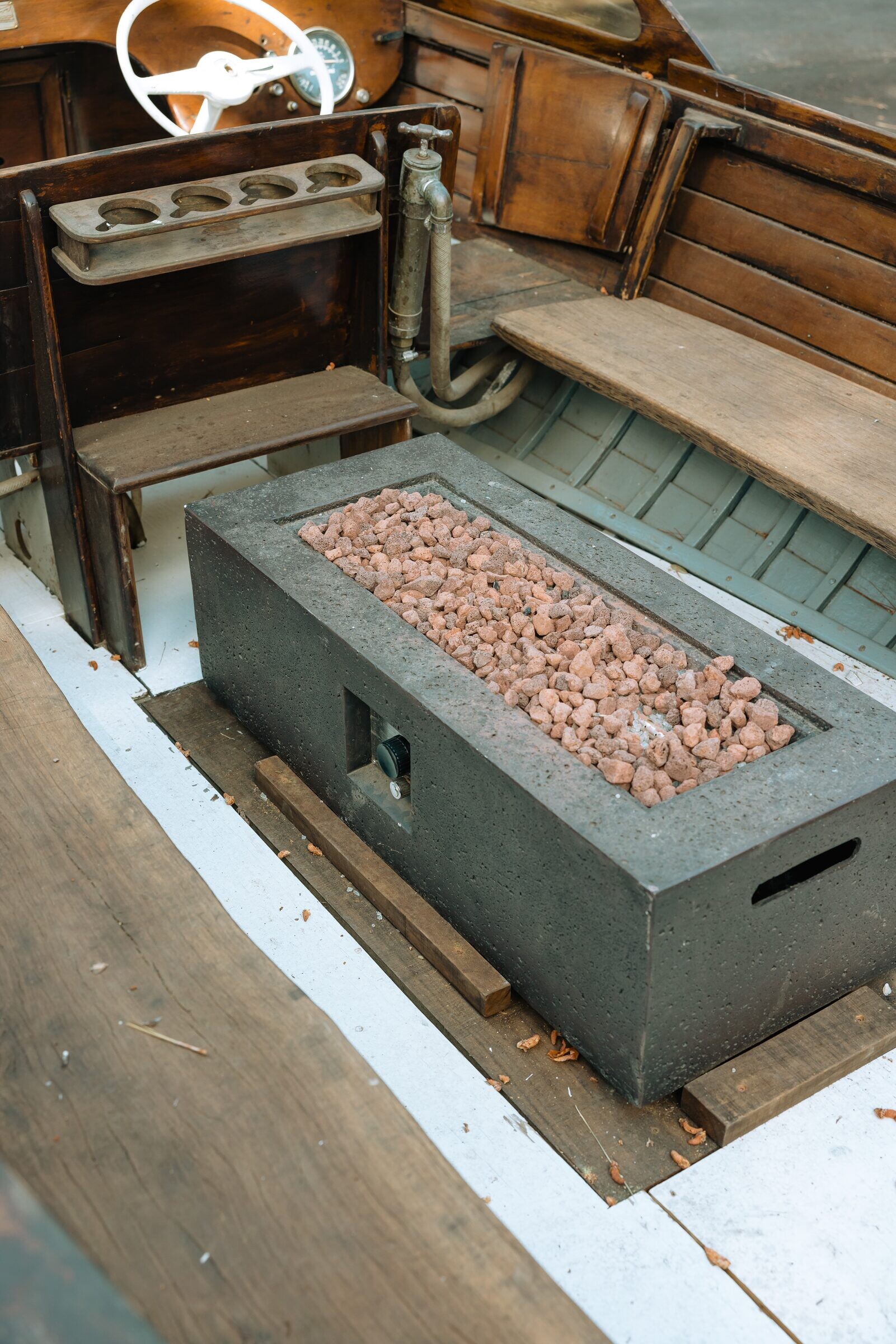 Vintage white boat reborn as an outdoor lava-rock fire pit in the pine courtyard